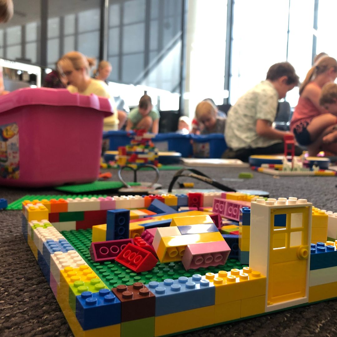 A structure of lego bricks, with soft focus kids in the background