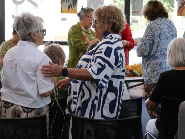 Artist and weaver Debbie Wood confers with a participant in the weaving workshop.