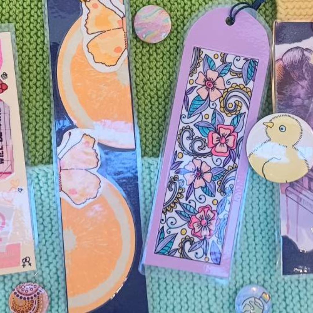 Hand-made bookmarks and badges are displayed on a pastel-coloured background