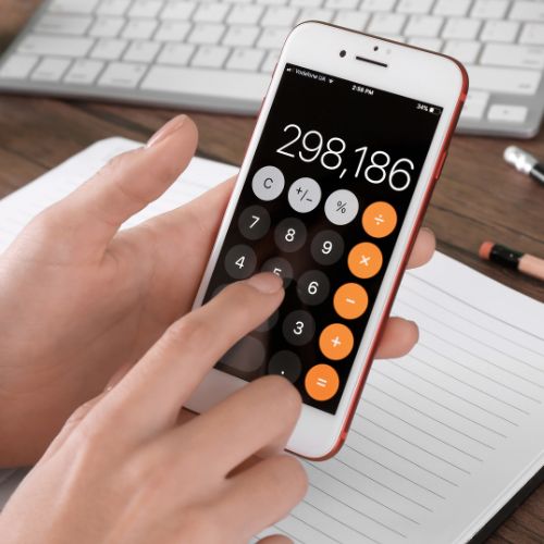 A hand holds an iPhone with its calculator on screen, showing 298,186