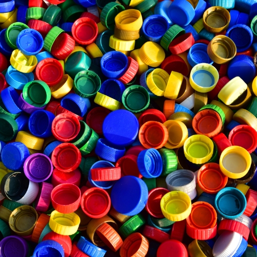 A close-up photo of many colourful lids in a pile.