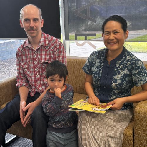 Leigh, Eddie and Valerie are sitting in a wheat-coloured couch, with the Wollundry Lagoon partly seen in the background